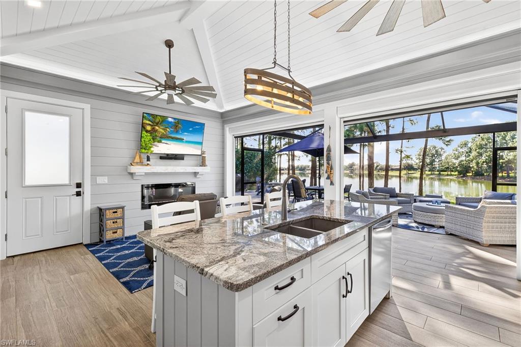 Kitchen with open floor plan, light stone countertops, white cabinetry, a kitchen bar, and a sunroom