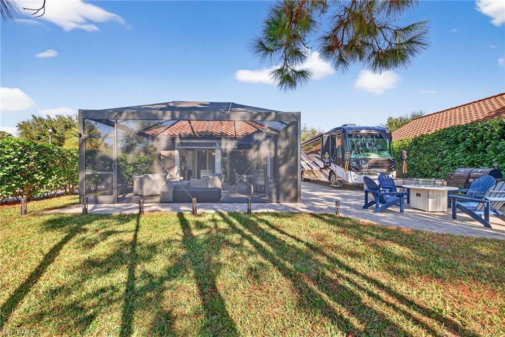 Rear view of house featuring a patio, a yard, a fire pit, and glass enclosure