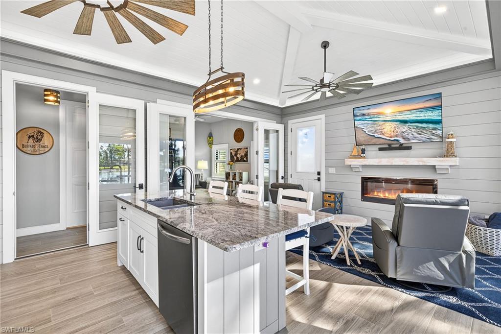Kitchen with a breakfast bar, light stone counters, white cabinetry, a kitchen island with sink, and light wood-style flooring