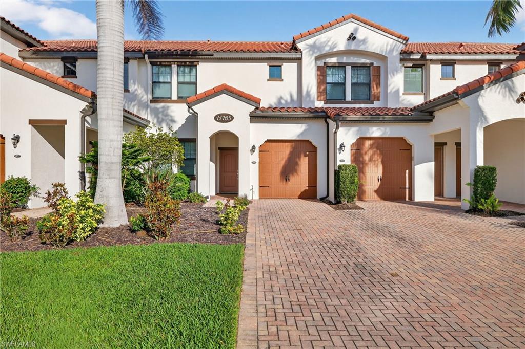 Mediterranean / spanish-style house with a tile roof, stucco siding, and a front lawn