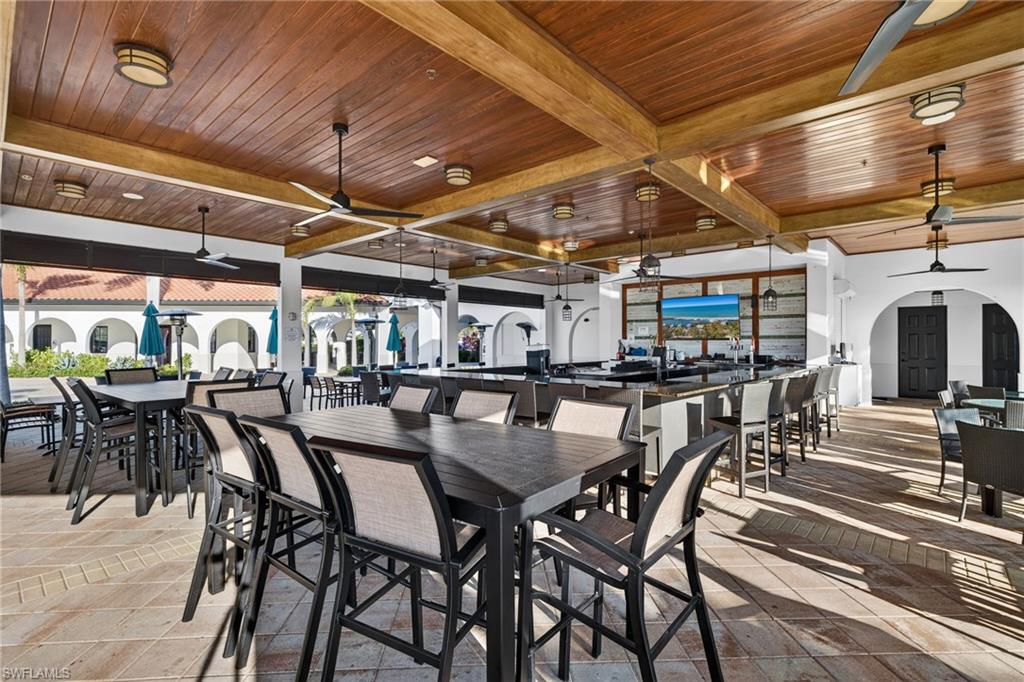 Dining space with ceiling fan, arched walkways, a wood ceiling with exposed beams, and stone tile flooring