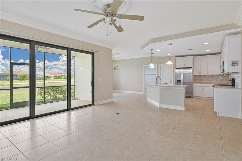 Open-concept living space with large format tile flooring, crown molding, and a ceiling fan