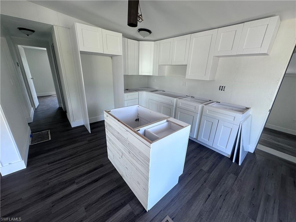 Kitchen with white cabinets, dark wood finished floors, a center island, and a ceiling fan