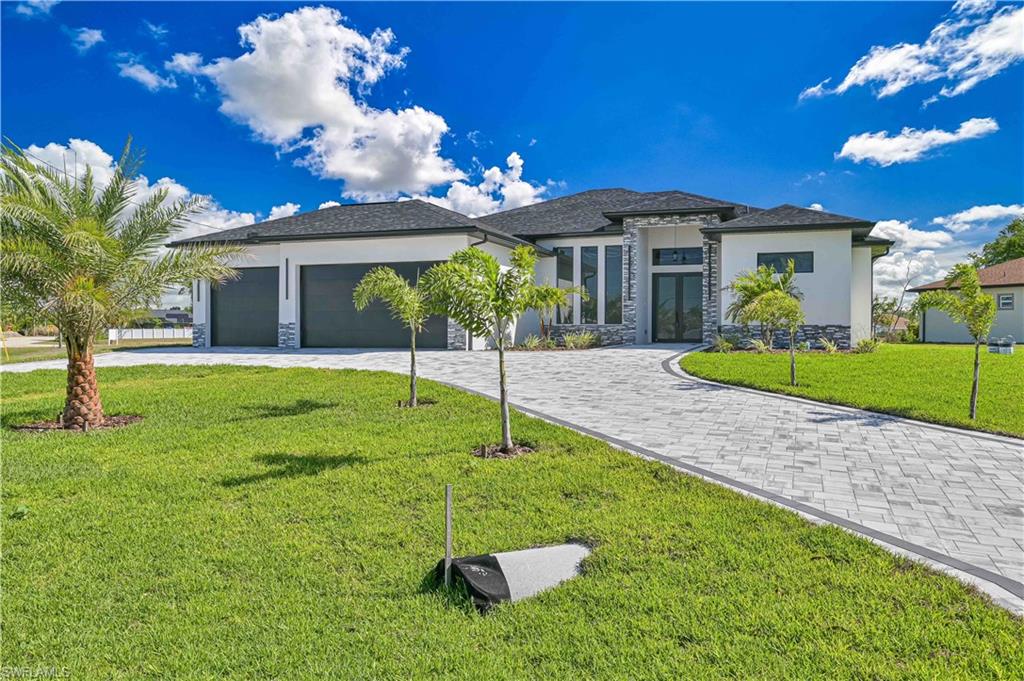 Prairie-style home with stone siding, a front yard, stucco siding, curved driveway, and an attached garage