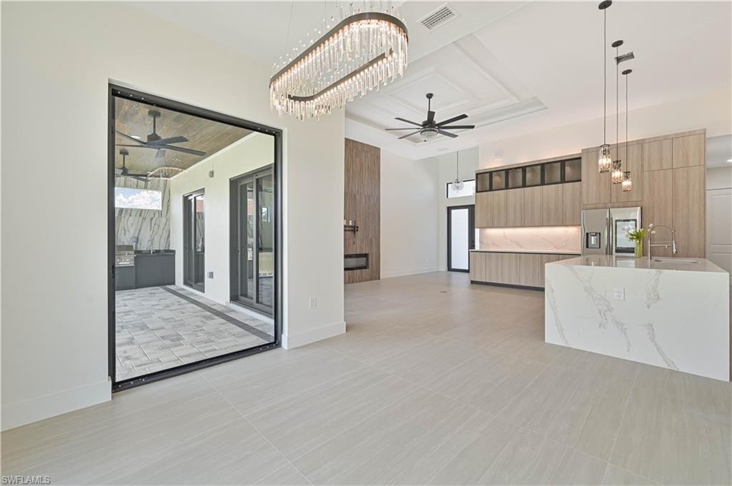 Kitchen featuring ceiling fan, a chandelier, stainless steel fridge with ice dispenser, open floor plan, and modern cabinets
