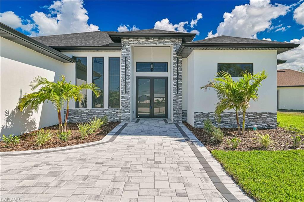 Doorway to property featuring french doors, stucco siding, stone siding, and roof with shingles