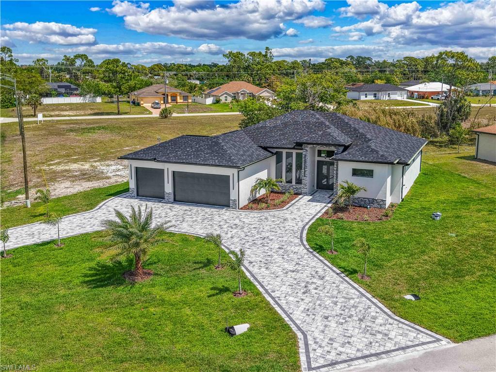 View of front of house with decorative driveway, a front lawn, an attached garage, and stucco siding