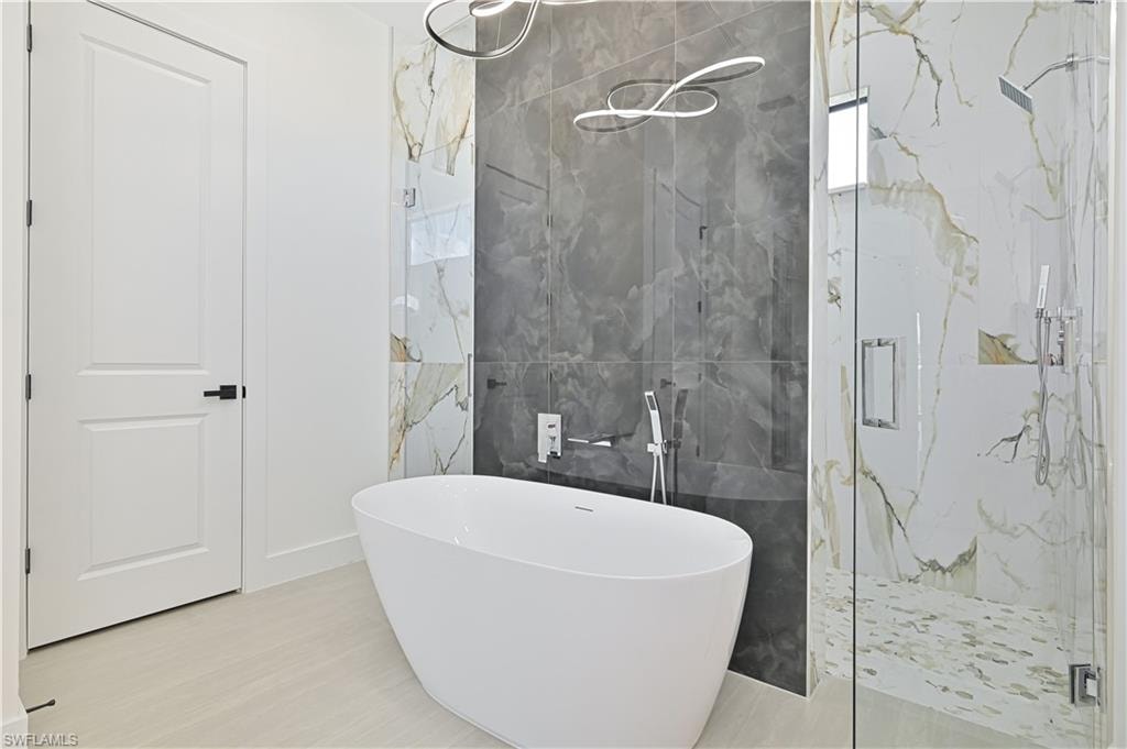 Full bath with a marble finish shower, tile walls, and a freestanding tub
