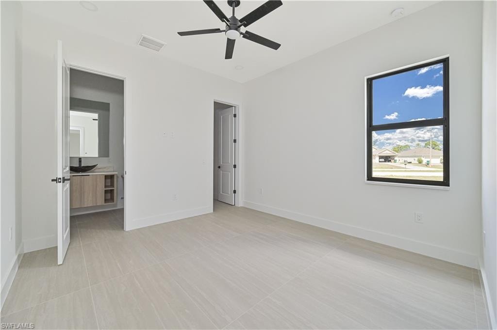 Unfurnished bedroom featuring a ceiling fan and connected bathroom