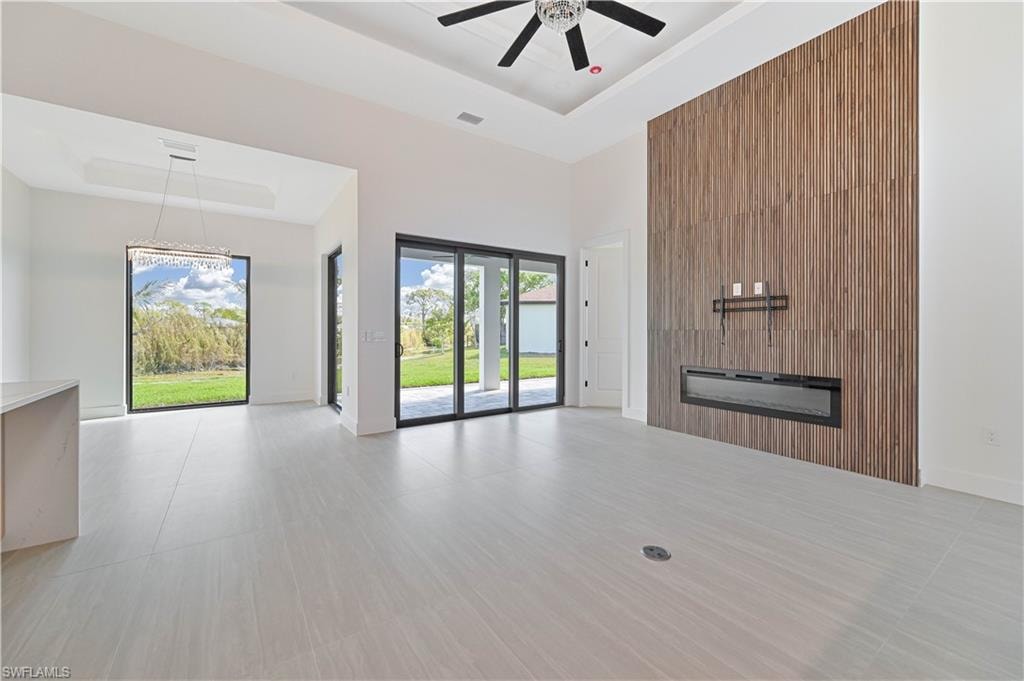 Unfurnished living room with a high tray ceiling and a ceiling fan