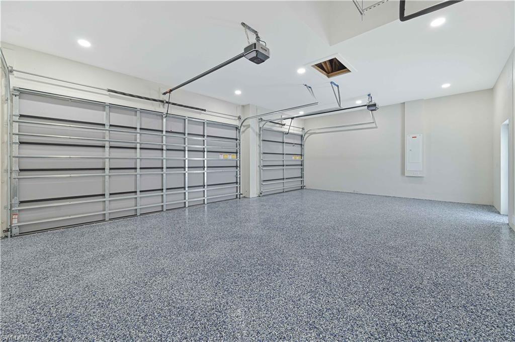 Garage with electric panel, recessed lighting, and a garage door opener