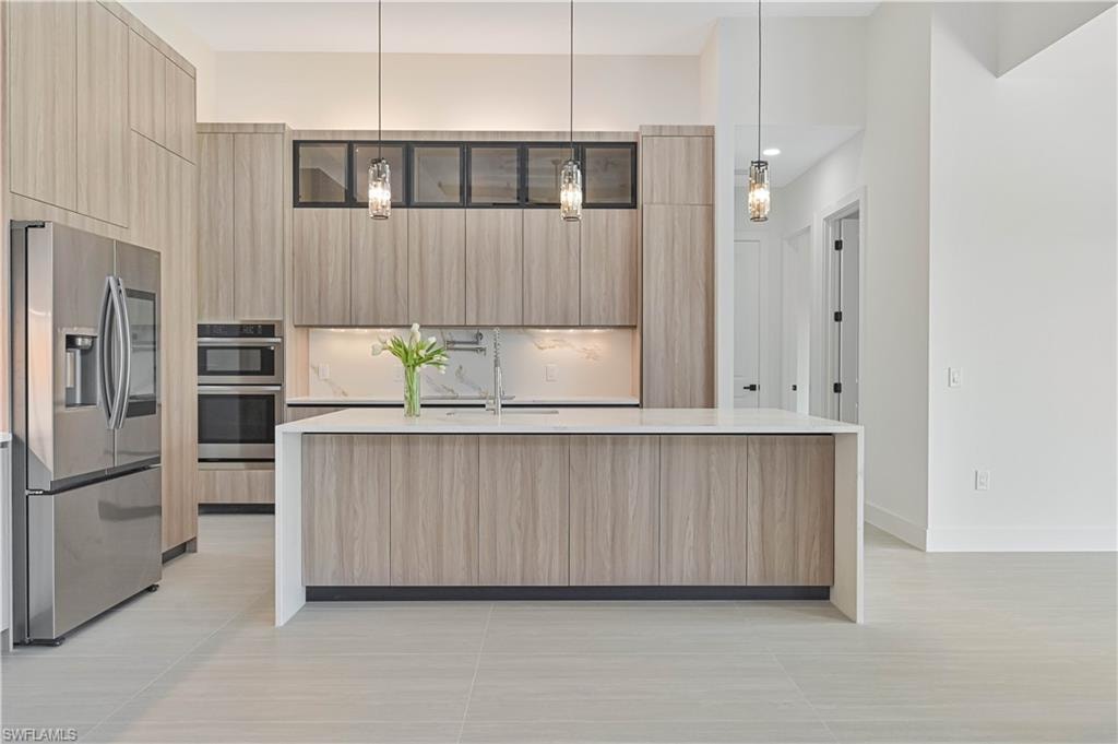 Kitchen with modern cabinets, stainless steel appliances, light stone countertops, and a spacious island