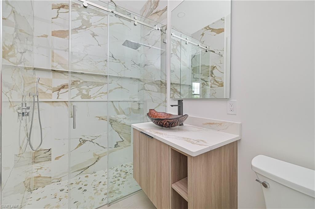 Full bath featuring a marble finish shower and vanity