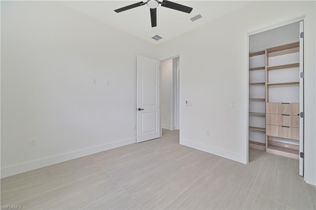 Unfurnished bedroom with a walk in closet and ceiling fan