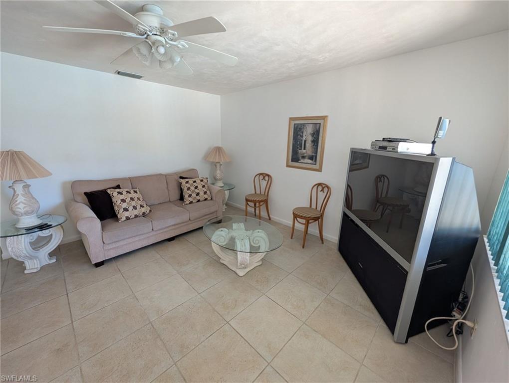 Living room featuring light tile patterned floors and ceiling fan