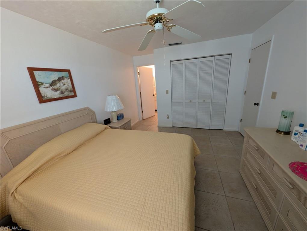 Bedroom with light tile patterned floors, a closet, and ceiling fan