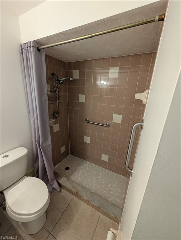 Full bathroom featuring a shower stall and light tile patterned floors