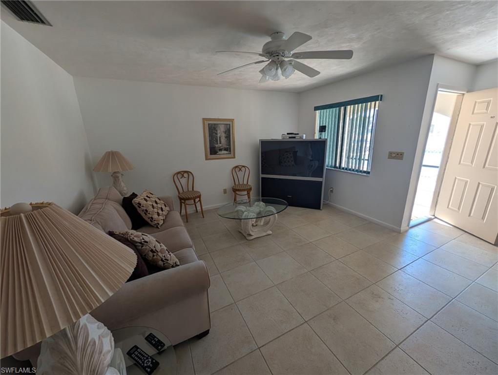 Living area featuring light tile patterned floors and a ceiling fan