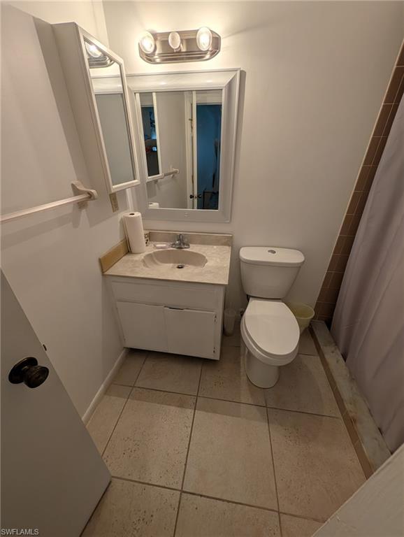 Full bath featuring vanity, curtained shower, and light tile patterned flooring