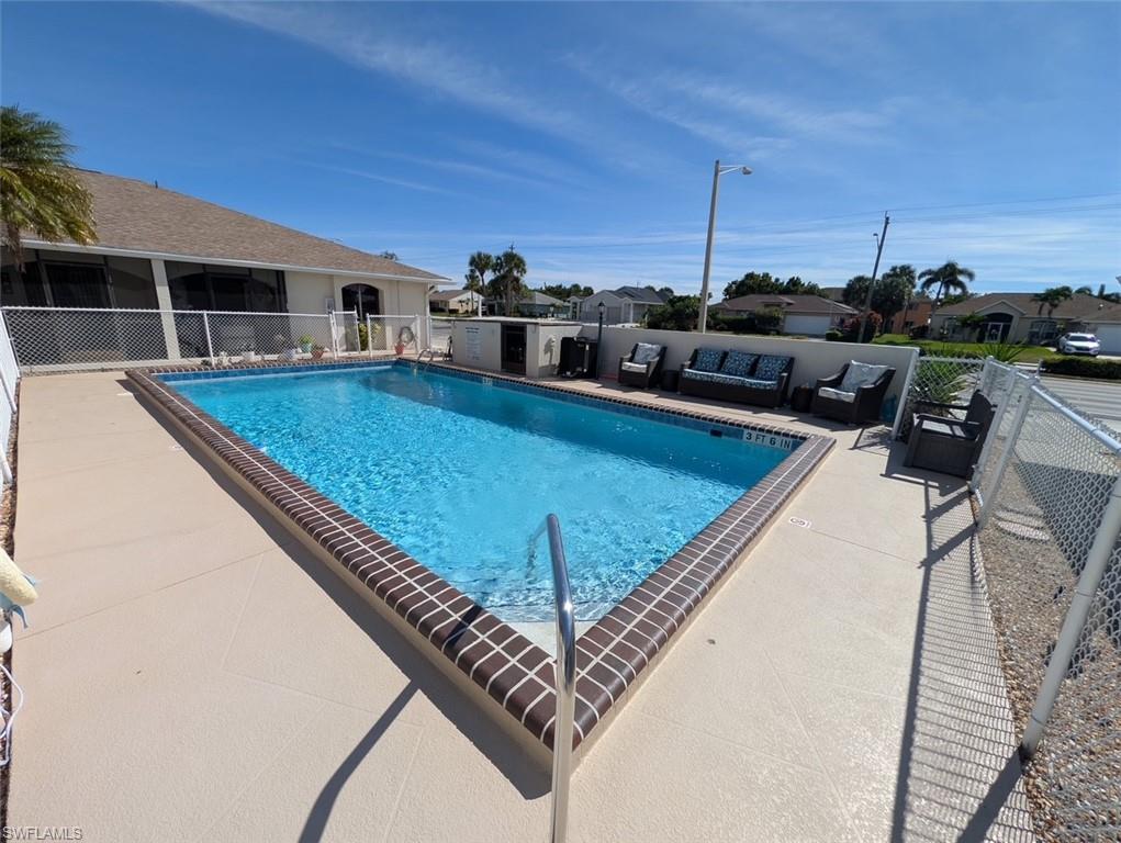 Community pool with an outdoor living space, a patio area, a residential view, and a sunroom