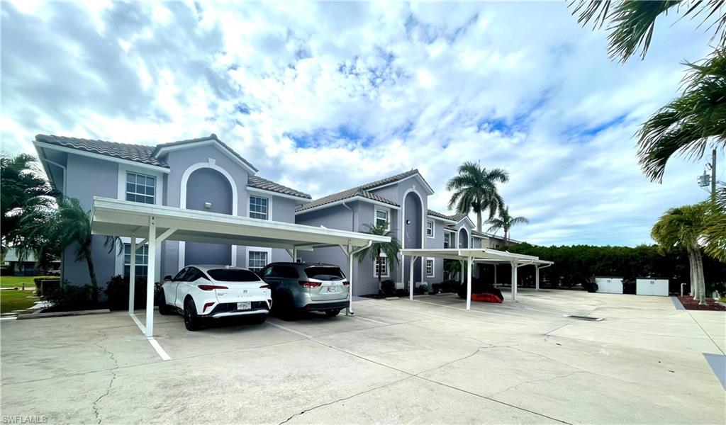 View of front facade with stucco siding, a tile roof, and covered parking