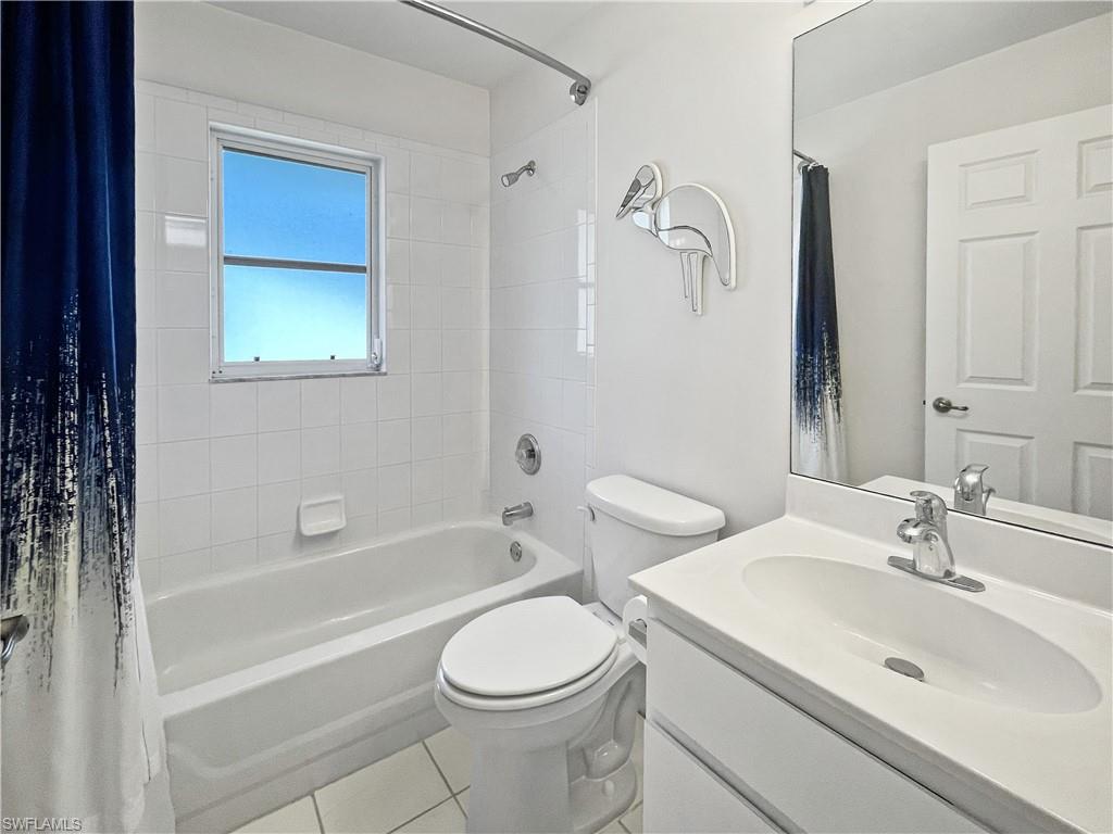 Guest bath with shower / tub combo with curtain, vanity, and light tile patterned floors