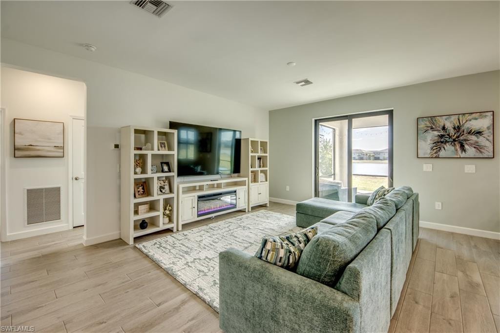 Living room with light wood-type flooring and a glass covered fireplace