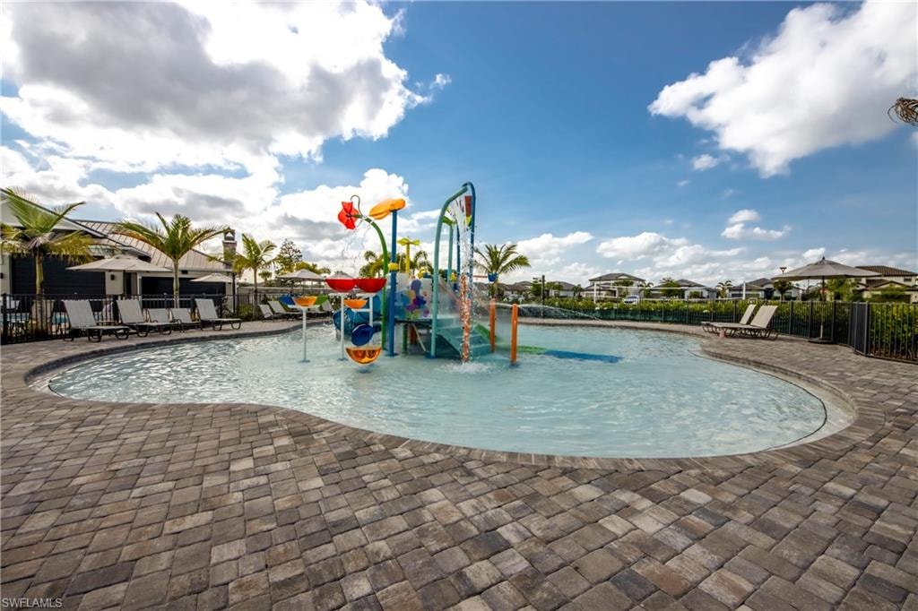 Community jungle gym featuring a water play area, a patio, a community pool, and a residential view