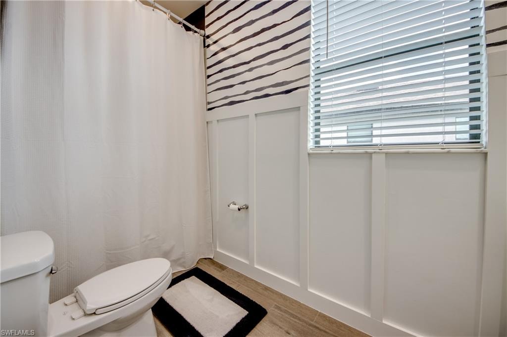 Bathroom featuring curtained shower, a decorative wall, and light wood-style flooring