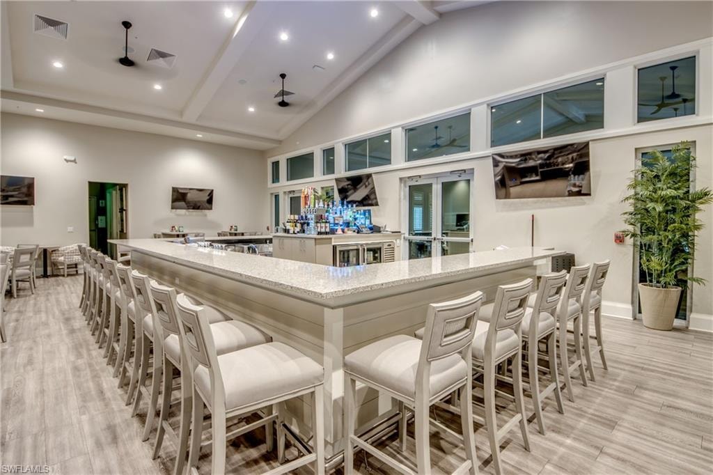 Kitchen featuring beamed ceiling, recessed lighting, light stone counters, a ceiling fan, and a kitchen breakfast bar