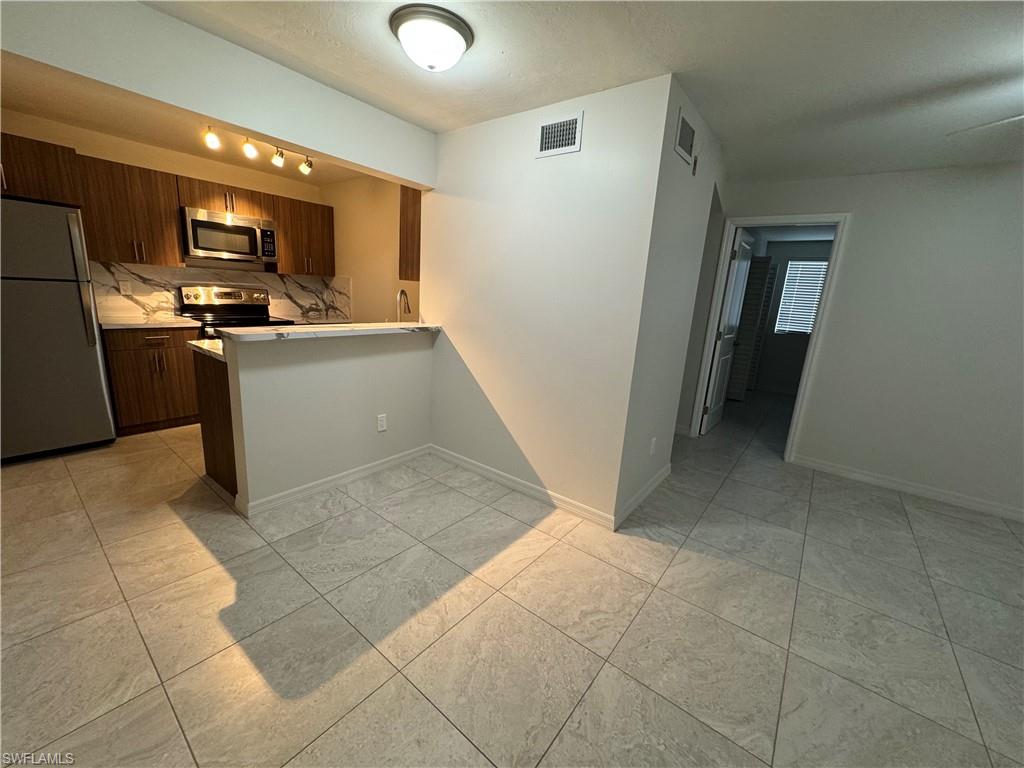 Kitchen featuring stainless steel appliances, a peninsula, a textured ceiling, modern cabinets, and dark brown cabinetry