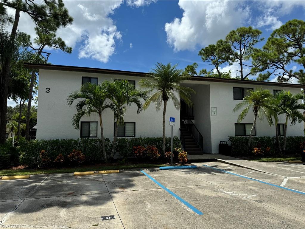 View of building exterior featuring uncovered parking and stairway