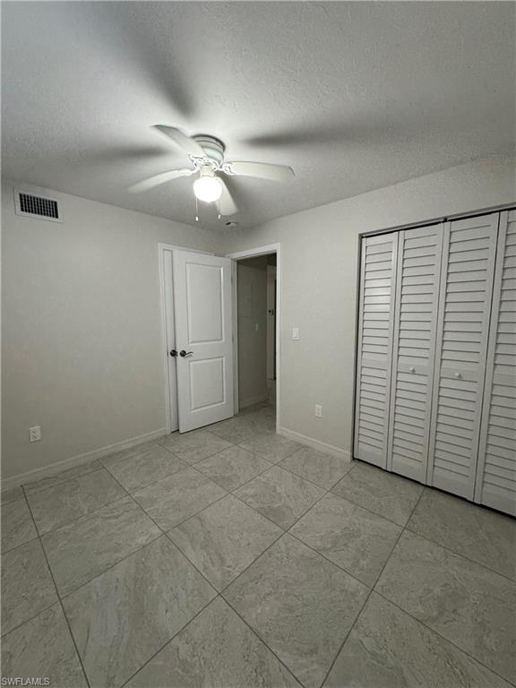 Unfurnished bedroom featuring a closet, a ceiling fan, and a textured ceiling