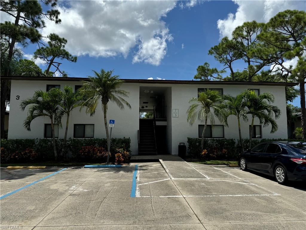 View of building exterior with uncovered parking and stairway