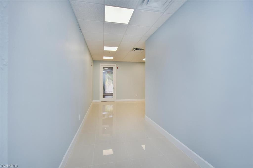 Hall with a drop ceiling and light tile patterned flooring