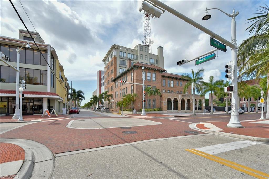 View of asphalt street featuring sidewalks, curbs, traffic lights, and street lights