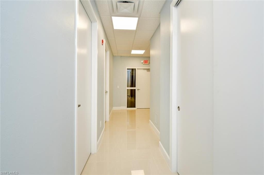 Corridor with a paneled ceiling and baseboards