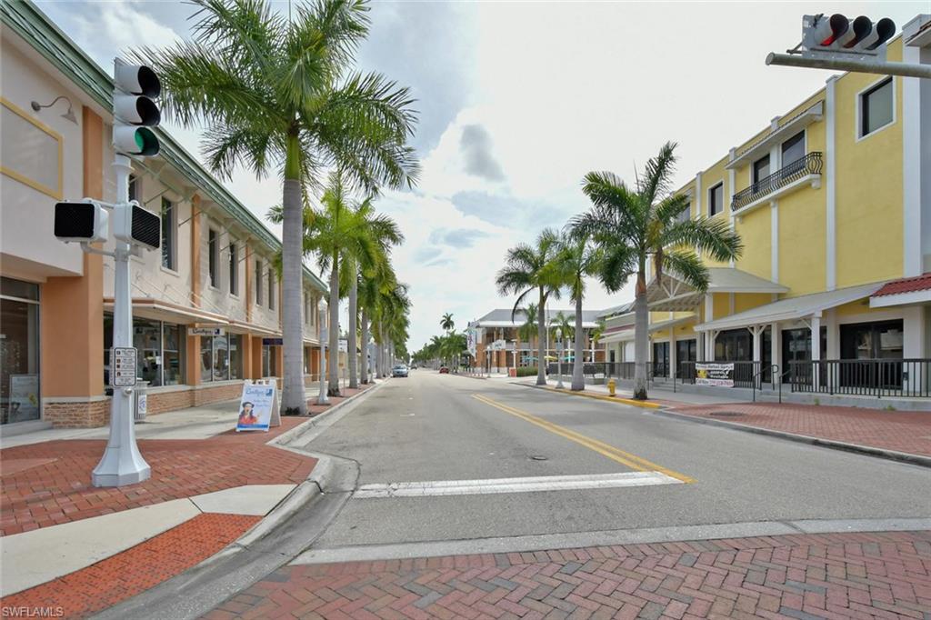 View of asphalt street featuring sidewalks, curbs, traffic lights, and street lights