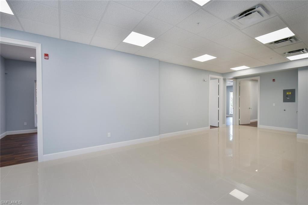 Empty room with light tile patterned flooring, a drop ceiling, and electric panel