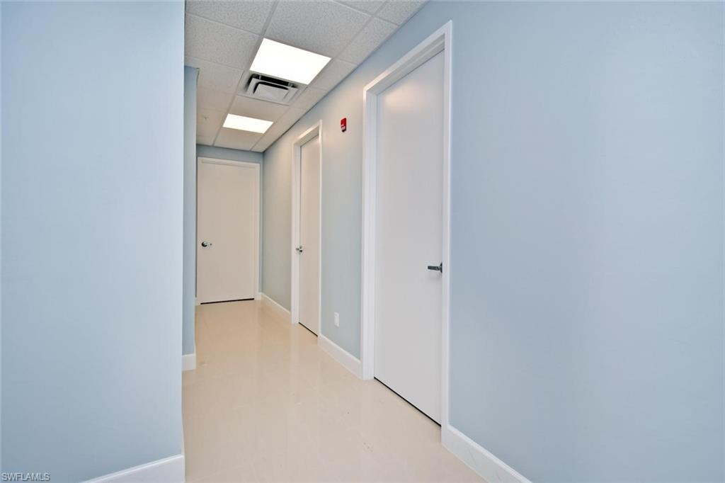 Hall with a paneled ceiling and baseboards