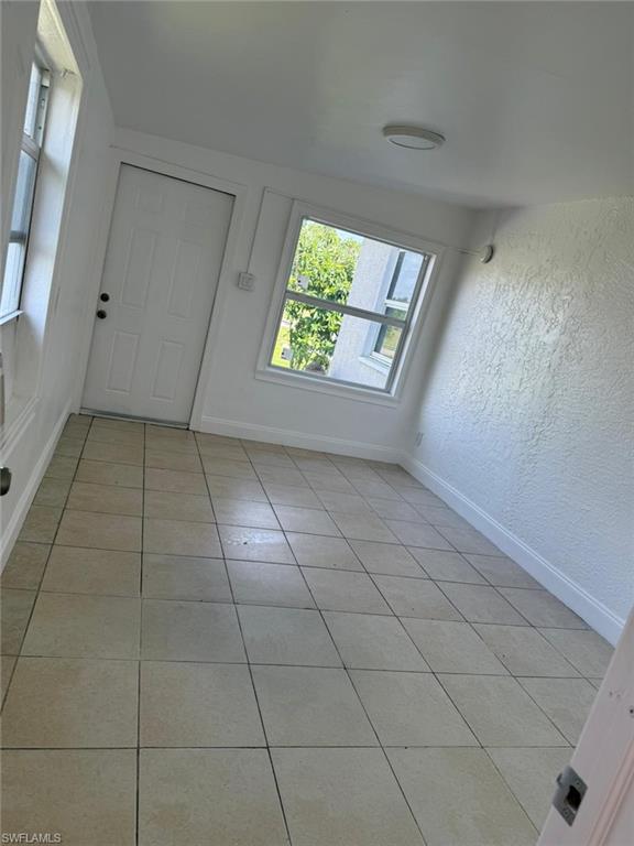 Foyer with light tile patterned floors and a textured wall
