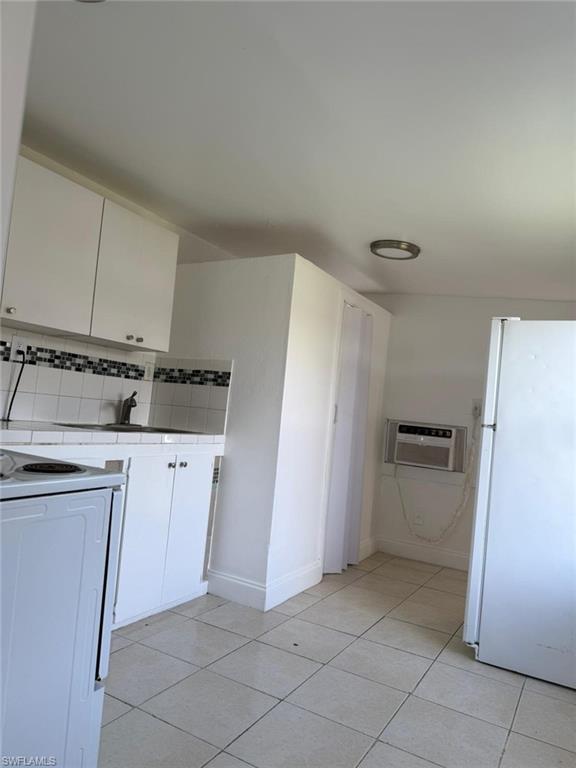 Kitchen featuring white appliances, tile counters, white cabinets, and tasteful backsplash