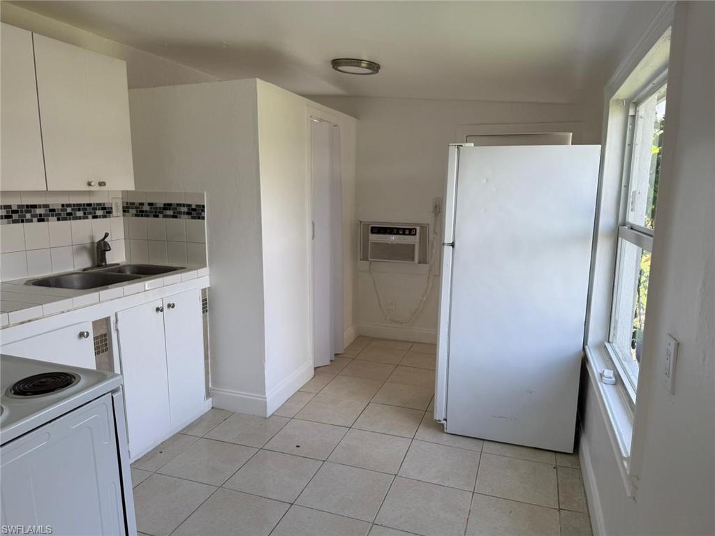 Kitchen featuring white cabinetry, white appliances, tile counters, decorative backsplash, and light tile patterned flooring