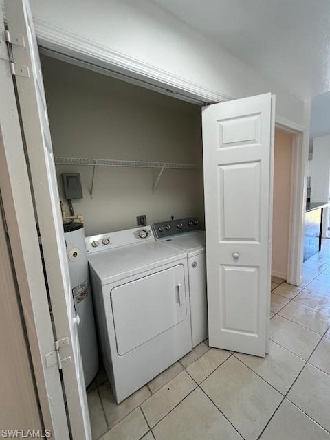 Washroom with water heater, light tile patterned flooring, and separate washer and dryer