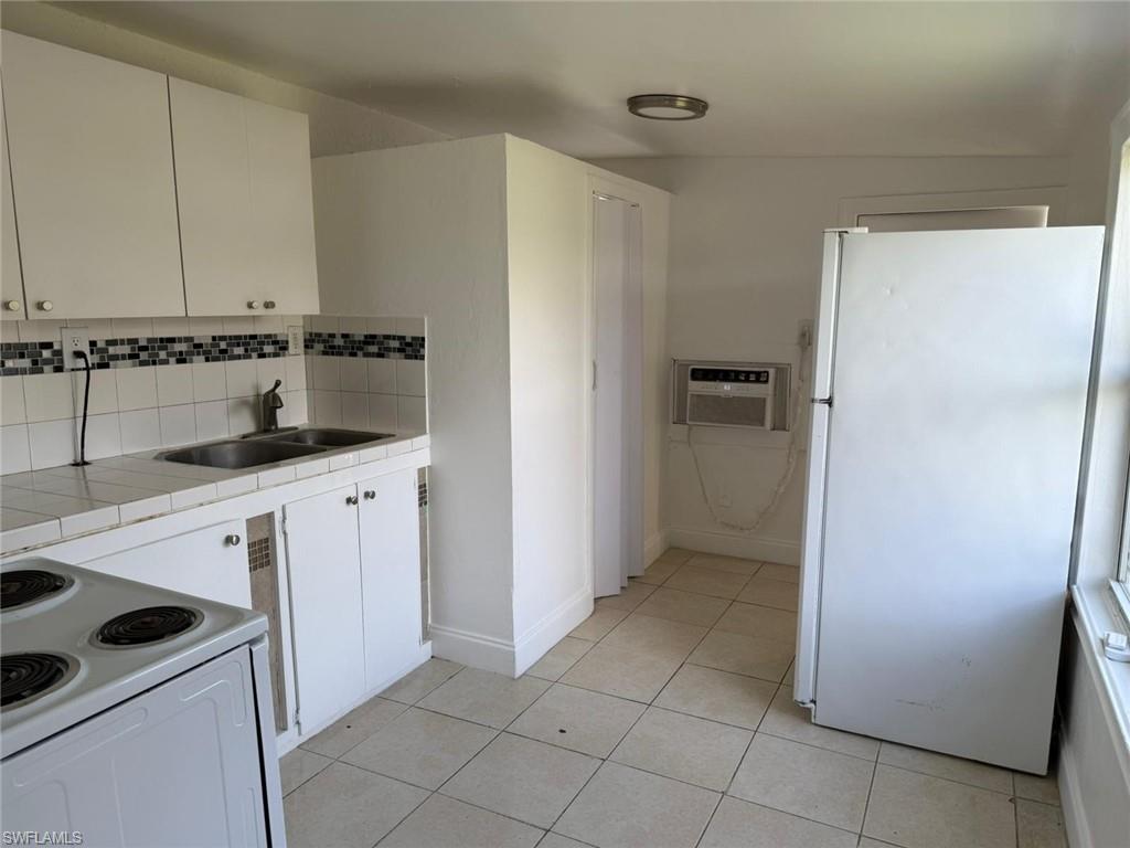 Kitchen featuring white cabinetry, tile countertops, white appliances, and backsplash