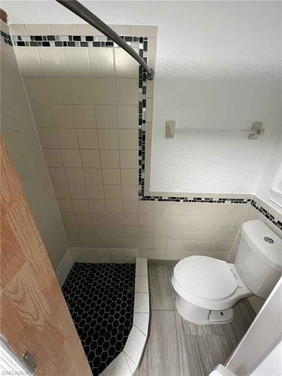 Bathroom featuring a stall shower, tile walls, and a wainscoted wall