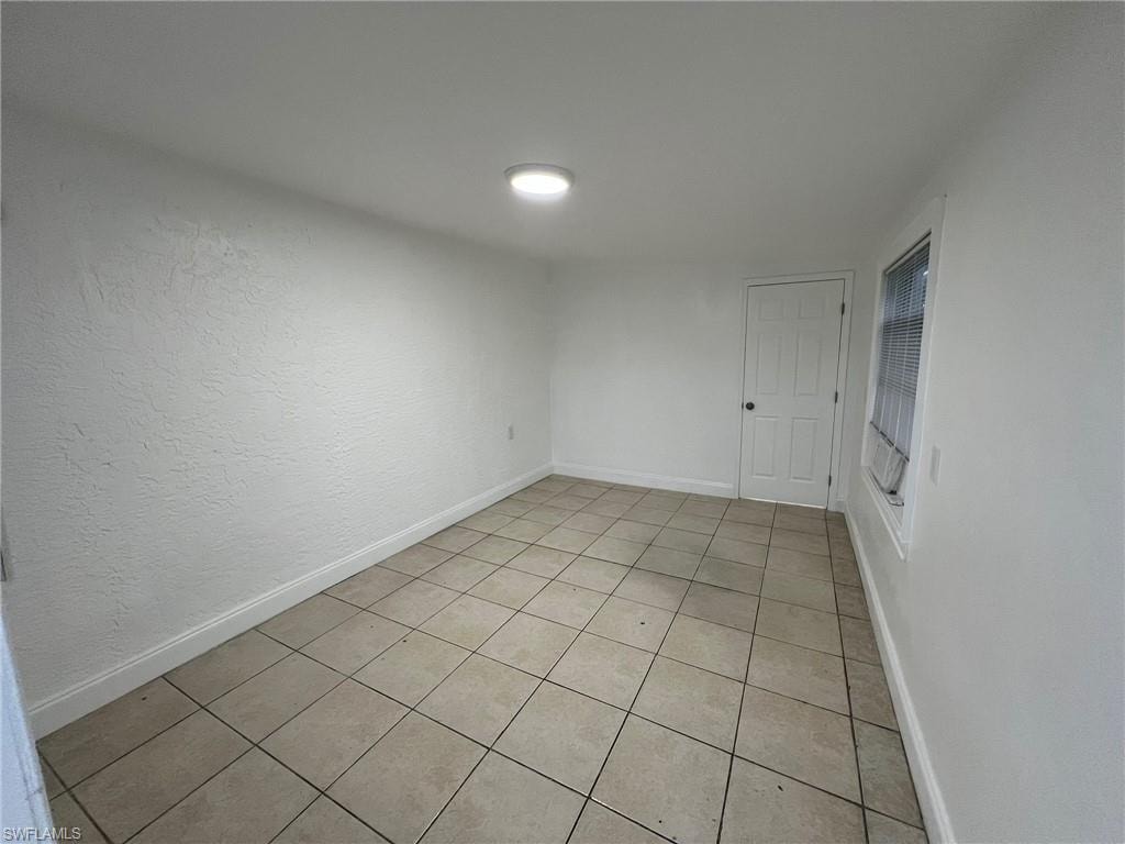 Empty room featuring baseboards and light tile patterned floors