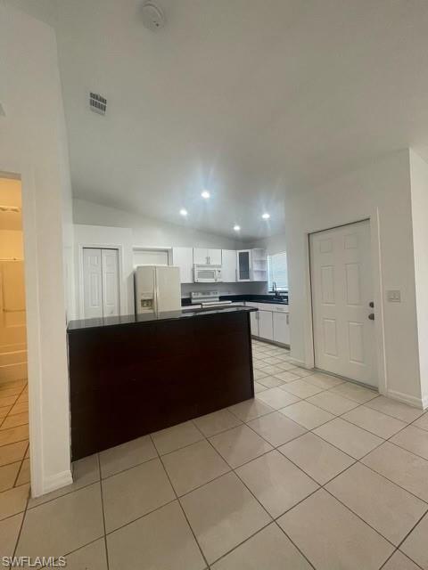 Kitchen with white cabinetry, dark countertops, white appliances, recessed lighting, and light tile patterned floors