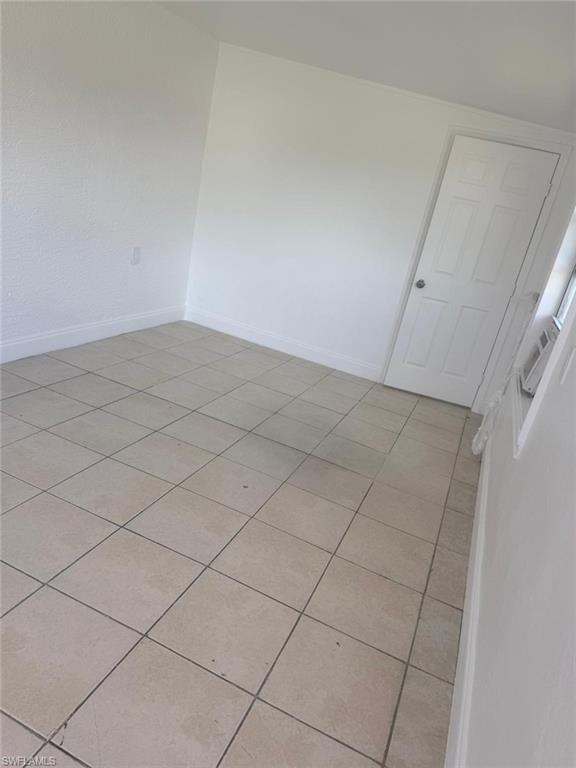Empty room featuring light tile patterned floors and baseboards