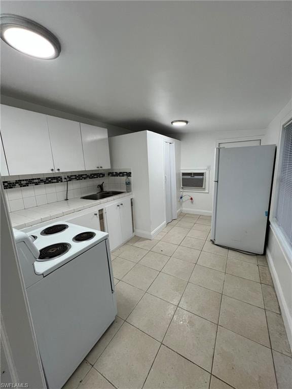 Kitchen featuring white cabinets, white appliances, tile countertops, backsplash, and light tile patterned floors